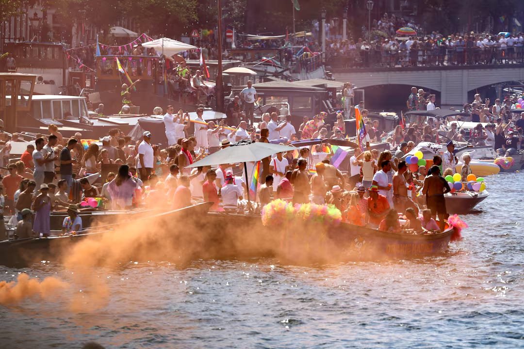 Thousands Gather for Amsterdam WorldPride Canal Parade Under Tight Security After Berlin Attack Participants celebrate during the Amsterdam WorldPride 2026 Canal Parade with rainbow flags and decorated boats.