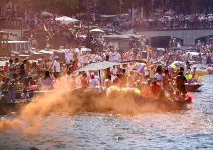 Participants celebrate during the Amsterdam WorldPride 2026 Canal Parade with rainbow flags and decorated boats.