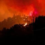 Smoke rises from the Bald Range wildfire over a residential street in Summerland, British Columbia